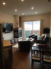 Living area featuring a glass covered fireplace, wood-type flooring, recessed lighting, and healthy amount of natural light