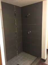 Full bath with a stall shower and a textured ceiling