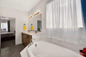 Bathroom with double vanity, connected bathroom, and a garden tub
