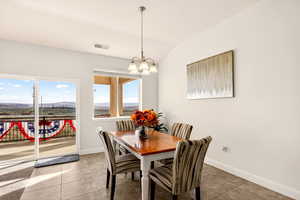 Dining space featuring vaulted ceiling, suspended lighting, light tile patterned floors, and a mountain view