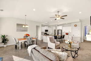 Living room featuring a ceiling fan and suspended lighting