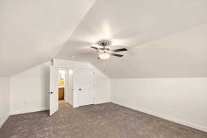 Bonus room featuring dark carpet and a ceiling fan