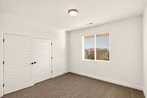 Unfurnished bedroom featuring a closet and dark carpet