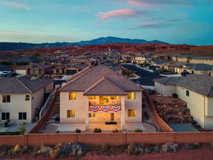 View of front facade with a fenced backyard, stucco siding, a mountain view, and a residential view