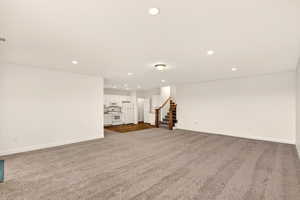 Unfurnished living room with dark carpet and recessed lighting