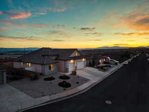 View of front of house featuring stone siding, concrete driveway, an attached garage, a mountain view, and stucco siding