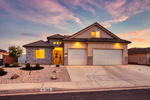 View of front facade with driveway, stone siding, stucco siding, and a garage
