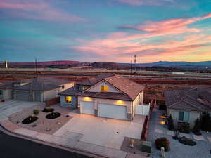 View of front facade featuring an attached garage, stone siding, driveway, stucco siding, and a gate