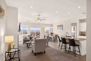 Living room with a mountain view, a ceiling fan, a chandelier, and light carpet