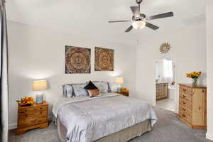 Bedroom featuring light colored carpet, vaulted ceiling, a ceiling fan, and ensuite bathroom