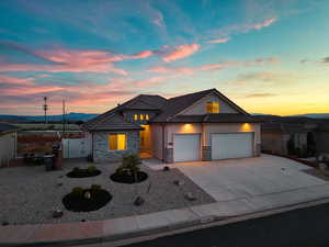 View of front facade featuring a gate, stone siding, an attached garage, concrete driveway, and stucco siding