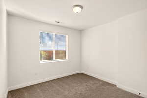 Empty room with baseboards and dark colored carpet