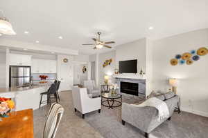 Living room with a fireplace, recessed lighting, and ceiling fan