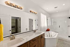 Full bathroom with double vanity, a marble finish shower, a bath, and recessed lighting
