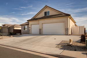 View of front of property with stucco siding, stone siding, concrete driveway, and a tiled roof