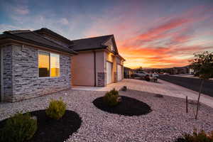 View of property exterior with stucco siding, driveway, stone siding, and a tiled roof