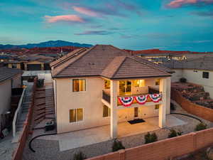 Rear view of property with stucco siding, a fenced backyard, and a patio