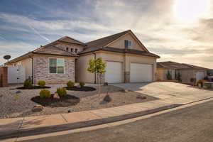 View of front facade featuring stone siding, stucco siding, concrete driveway, an attached garage, and a gate