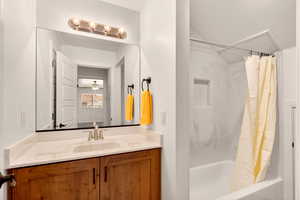 Bathroom featuring vanity, shower / tub combo with curtain, and a ceiling fan