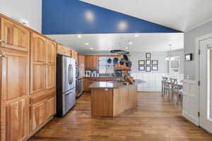 Kitchen with freestanding refrigerator, wainscoting, dark wood finished floors, a center island, and a decorative wall