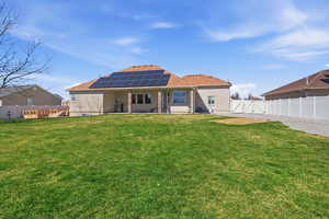 Rear view of property featuring a gate, roof mounted solar panels, a patio area, a fenced backyard, and stucco siding