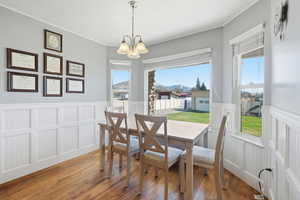 Dining area featuring hardwood / wood-style floors, a chandelier, a mountain view, ornamental molding, and a wainscoted wall