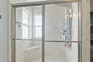 Bathroom with a marble finish shower and healthy amount of natural light