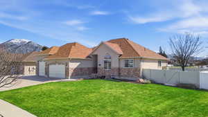 View of front of house with stucco siding, an attached garage, a gate, stone siding, and concrete driveway