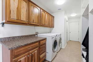 Laundry room with cabinet space, washer and dryer, and light tile patterned floors