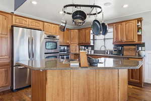 Kitchen featuring stainless steel appliances, a center island, recessed lighting, dark stone counters, and crown molding