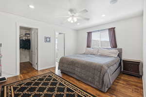 Bedroom featuring dark wood-type flooring, a spacious closet, a ceiling fan, and recessed lighting