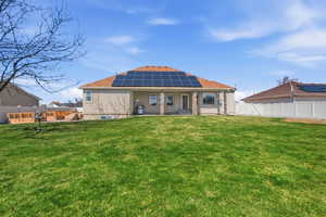 Back of property featuring roof mounted solar panels, a patio, a gate, and a fenced backyard