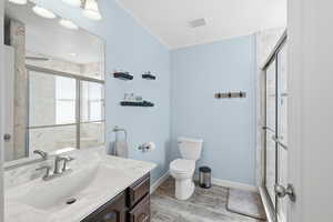 Bathroom featuring a marble finish shower, vanity, and wood finish floors