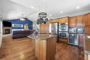Kitchen with a center island, wine cooler, open floor plan, stainless steel appliances, and dark wood-style flooring