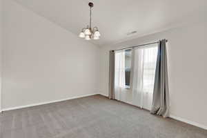 Empty room featuring a chandelier, light carpet, and lofted ceiling