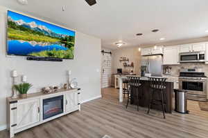 Kitchen with a barn door, stainless steel appliances, a kitchen island, a kitchen breakfast bar, and light wood finished floors