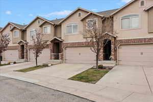 Traditional-style home with stucco siding, an attached garage, concrete driveway, and stone siding