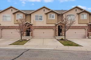 View of front of property featuring stucco siding, concrete driveway, a garage, and brick siding