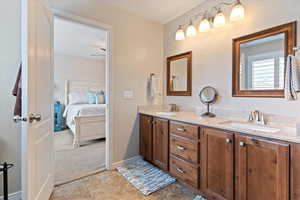 Ensuite bathroom with double vanity, light tile patterned flooring, and light colored carpet