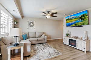 Living area with light wood-style floors and a ceiling fan
