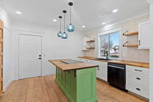 Kitchen featuring wood counters, decorative backsplash, crown molding, pendant lighting, and black appliances