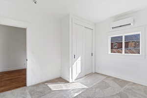 Unfurnished bedroom featuring a mini split for heating / cooling, light carpet, and a closet