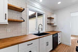 Kitchen with wood counters, open shelves, crown molding, white cabinetry, and light wood-style flooring