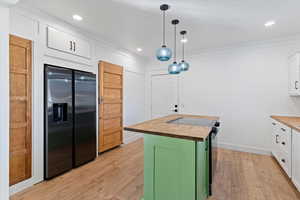 Kitchen featuring butcher block counters, a center island, black fridge, electric stove, and dual tone cabinets