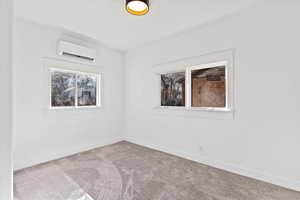 Empty room featuring a mini split for heating / cooling and light carpet