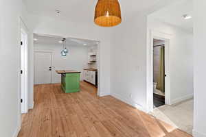 Kitchen featuring wood counters, light wood finished floors, decorative light fixtures, two tone cabinets, and open shelves