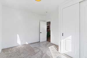 Unfurnished bedroom featuring light carpet and a closet