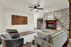 Living room featuring a large fireplace, a ceiling fan, and wood finished floors