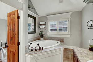 Full bathroom featuring a bath, vaulted ceiling, and vanity