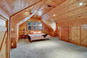 Bedroom with wood walls, a vaulted wood ceiling, and carpet floors